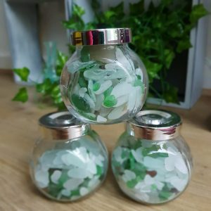 a photo of 3 glass jars filled with colourful green, blue, brown and white frosted glass that has been worn down by the action of the ocean. 